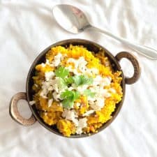 A picture of Comforting Bulgur Wheat Daliya garnished with cottage cheese and coriander and served against a white background.