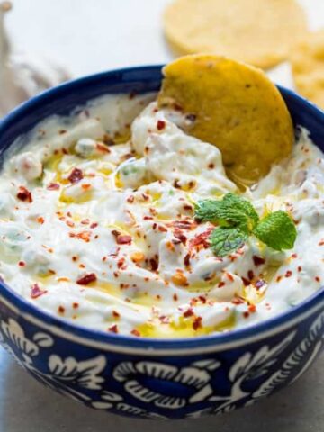 A close up of A picture of Garlicky yogurt party dip served in a blue bowl with chips