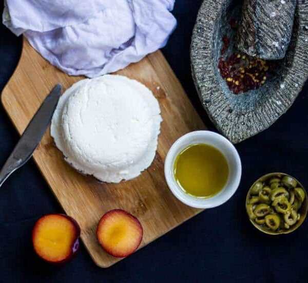 A picture of Homemade Cream Cheese on a wooden board along with Olive oil and Plum.