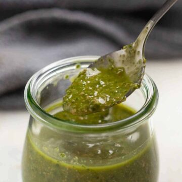 Herb vinaigrette in a jar with a spoon being taken out