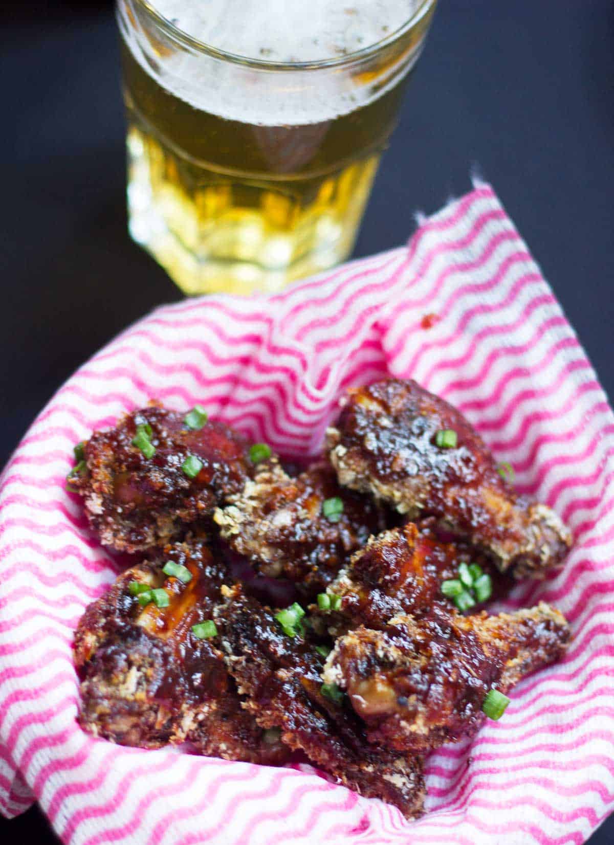 Baked Sticky Chicken Wings served in a bowl with beer.