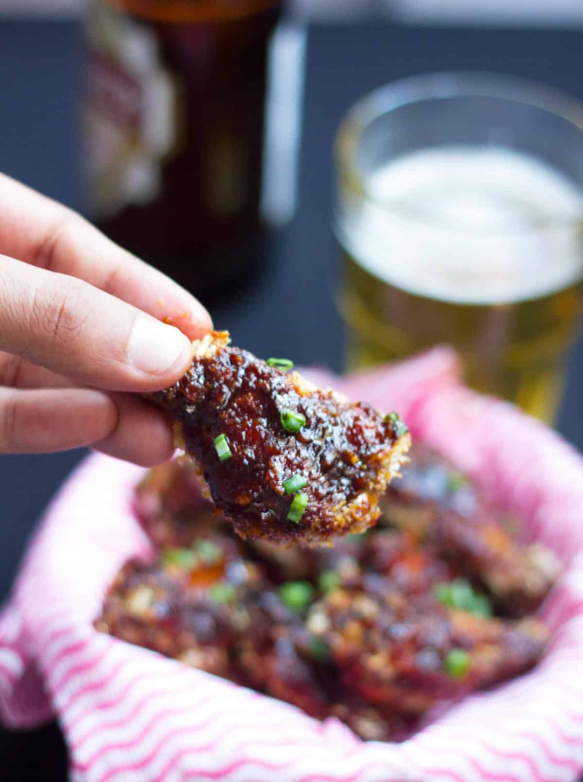 Picking a baked sticky chicken wing up.