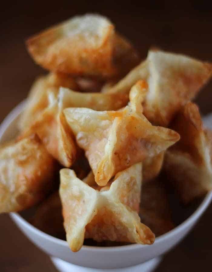 Cheese samosas stacked together in a white bowl