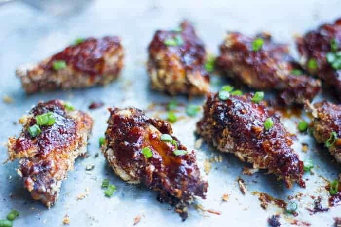 Baked sticky chicken wings garnished with spring onions and placed on butter paper