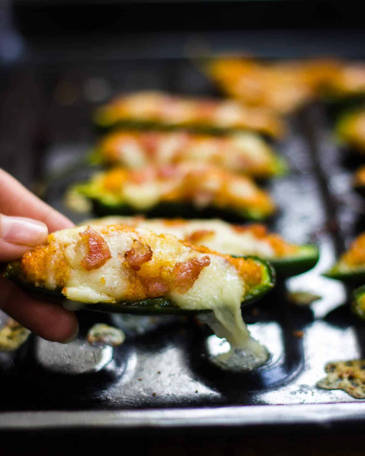 Baked jalapeno popper being picked up from the tray.
