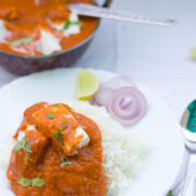 Healthy Paneer Makhani garnished with coriander and served with rice and a side of chopped onions in a white plate.