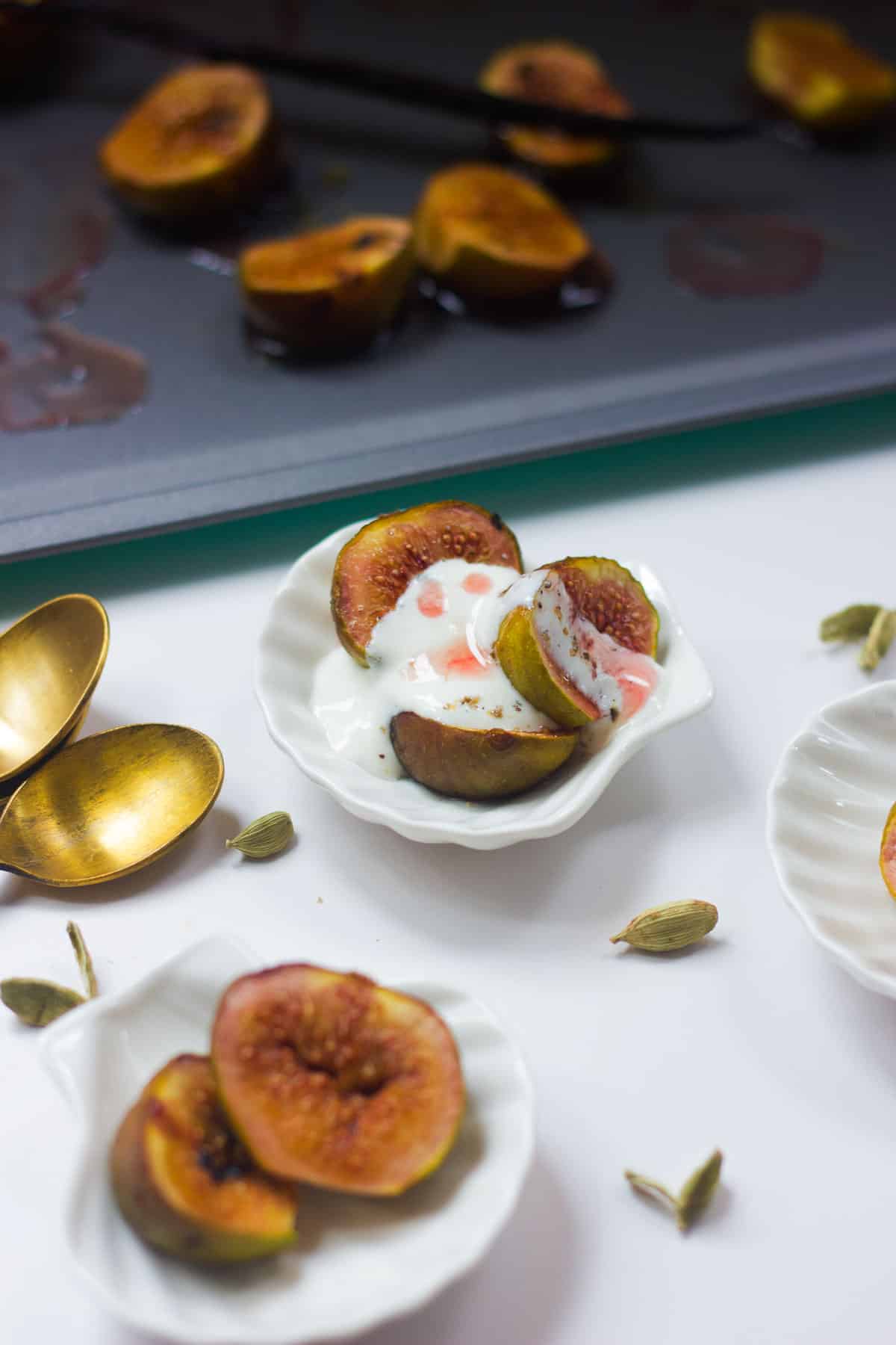 Roasted figs with cardamom yogurt served in tiny white bowls.