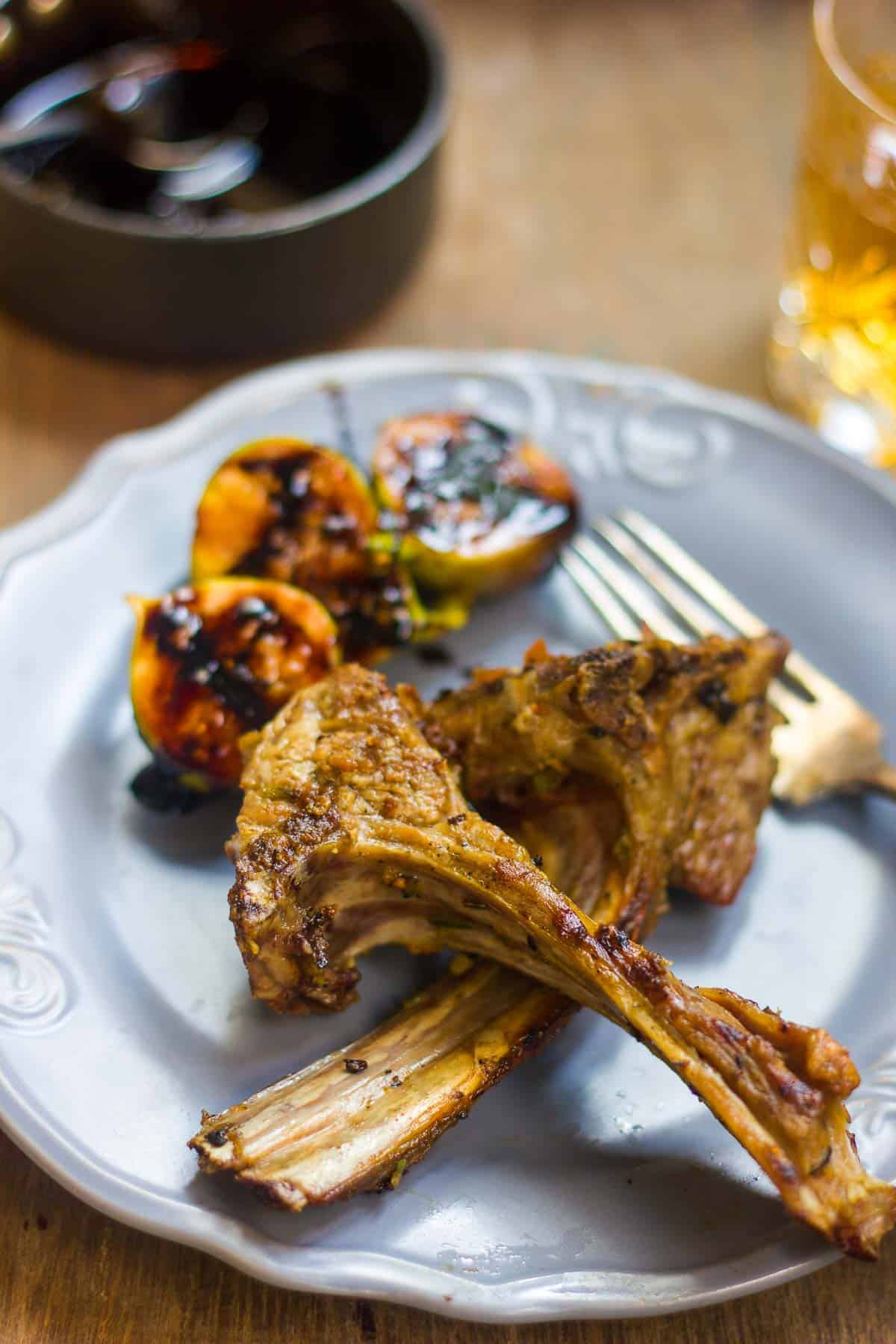 Spiced lamb chops served with figs and balsamic reduction on a blue plate.