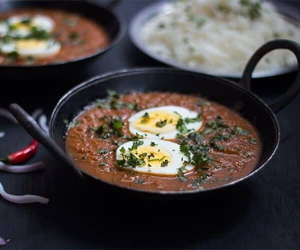 The egg curry garnished with coriander and served with rice.