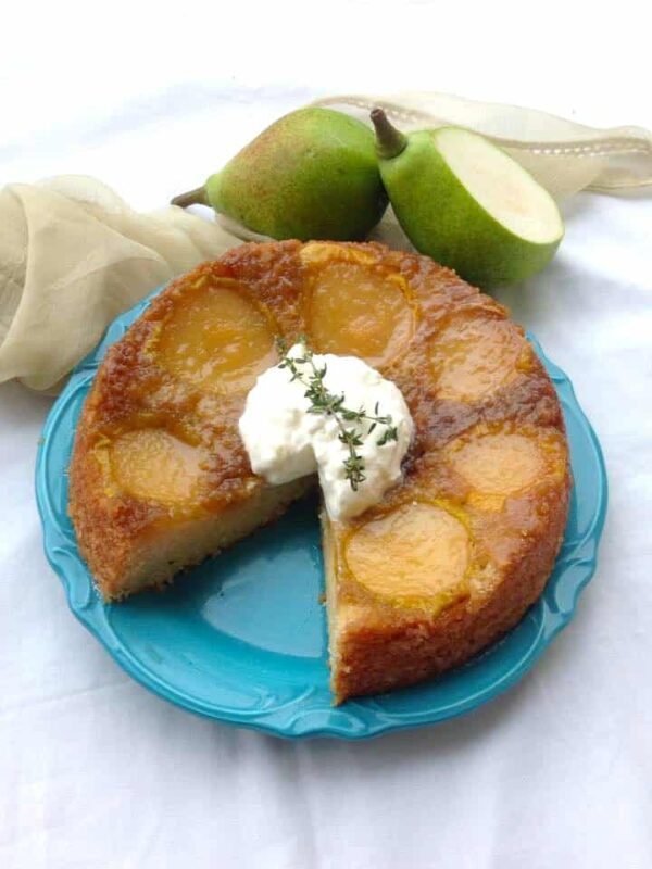 A slice stolen from the Upside Down Pear Cake served with whipped cream.