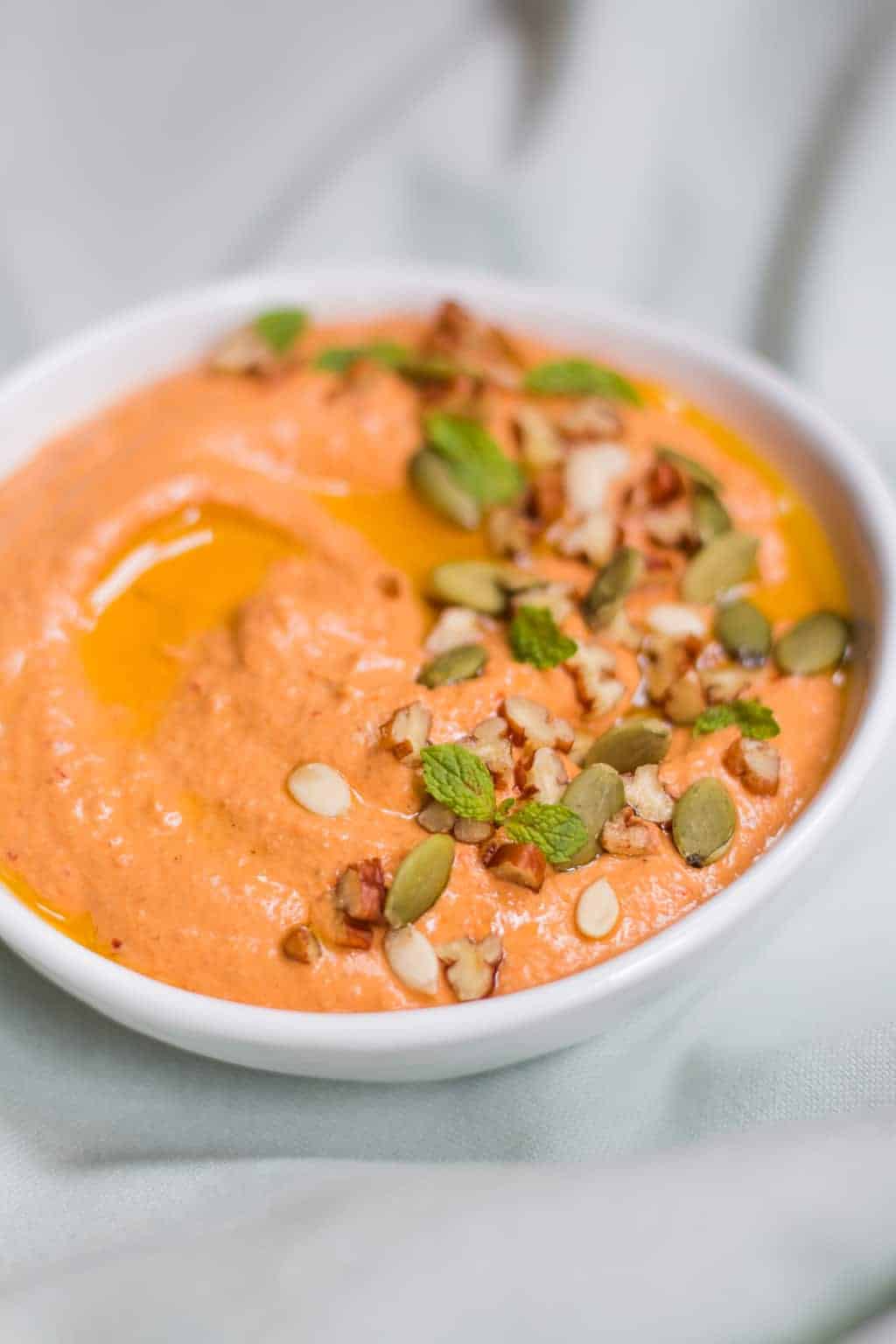 close up lebanese pecan red pepper dip garnished with pumpkin seeds served in a white bowl