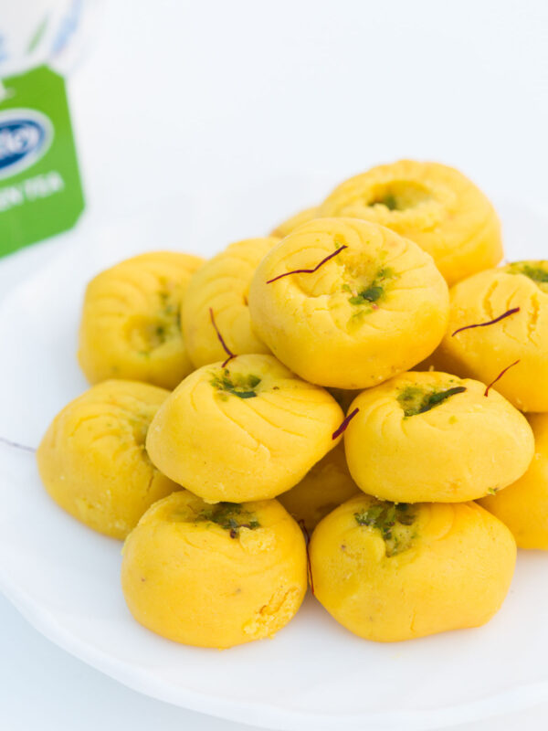 Easy Kesar Pedas served on a white plate with a side of Tetley green tea.