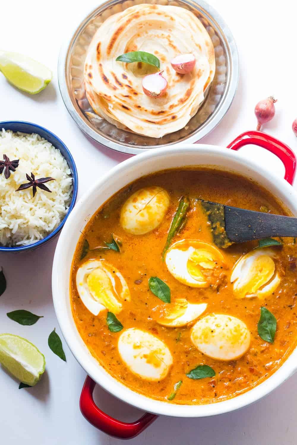 South Indian Style Egg Curry in a pot with steamed rice and malabar parathas