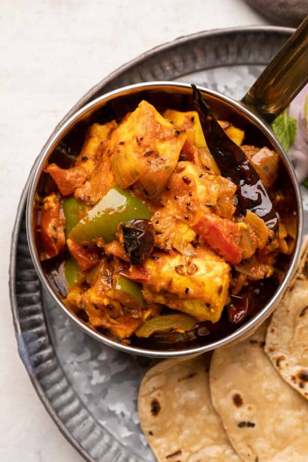 Achari Paneer served in a copper steel bowl with rotis on the side