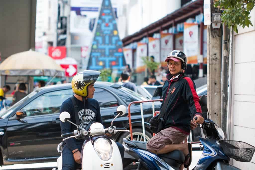 Two men on their scooty on a busy road in Bangkok