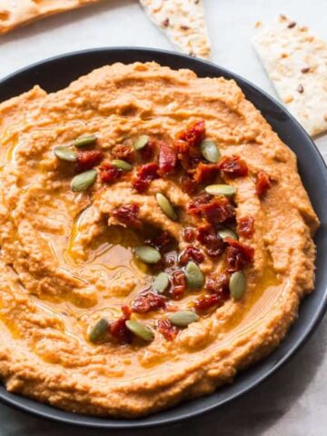 Sundried tomato hummus served in a black bowl with lavash.