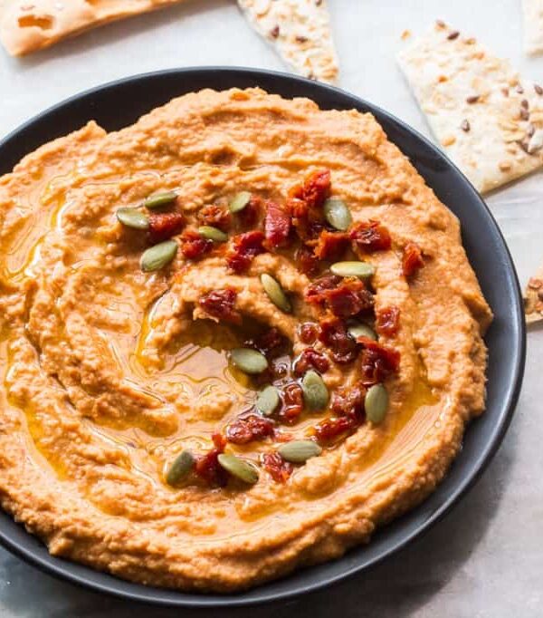Sundried tomato hummus served in a black bowl with lavash.