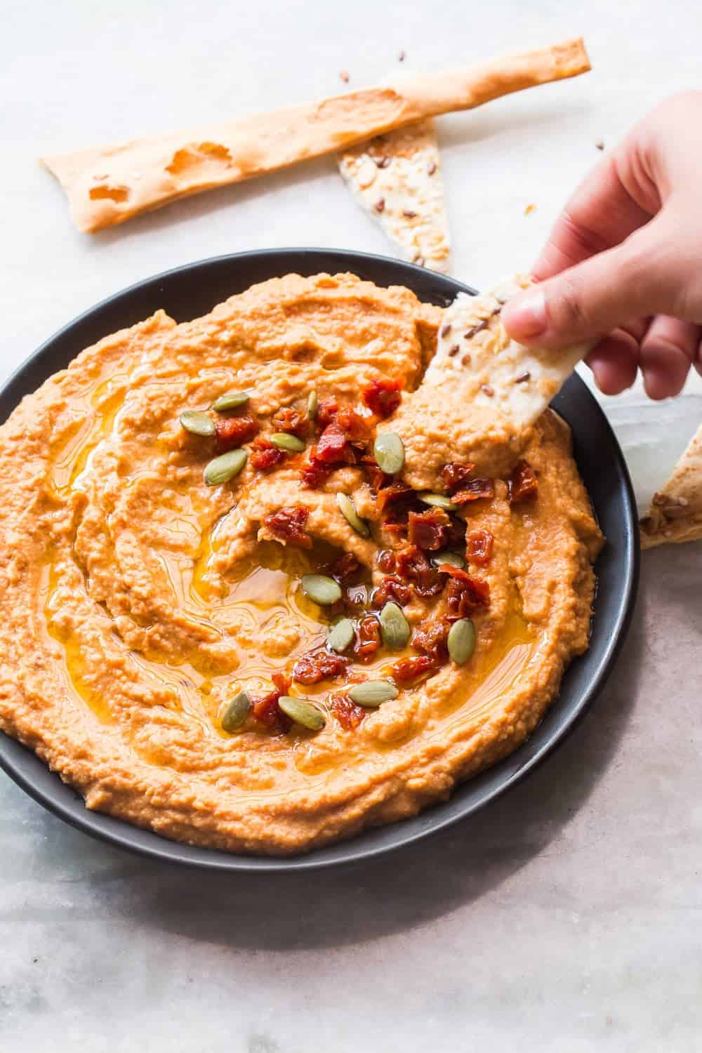 lavash being dipped into the bowl of hummus