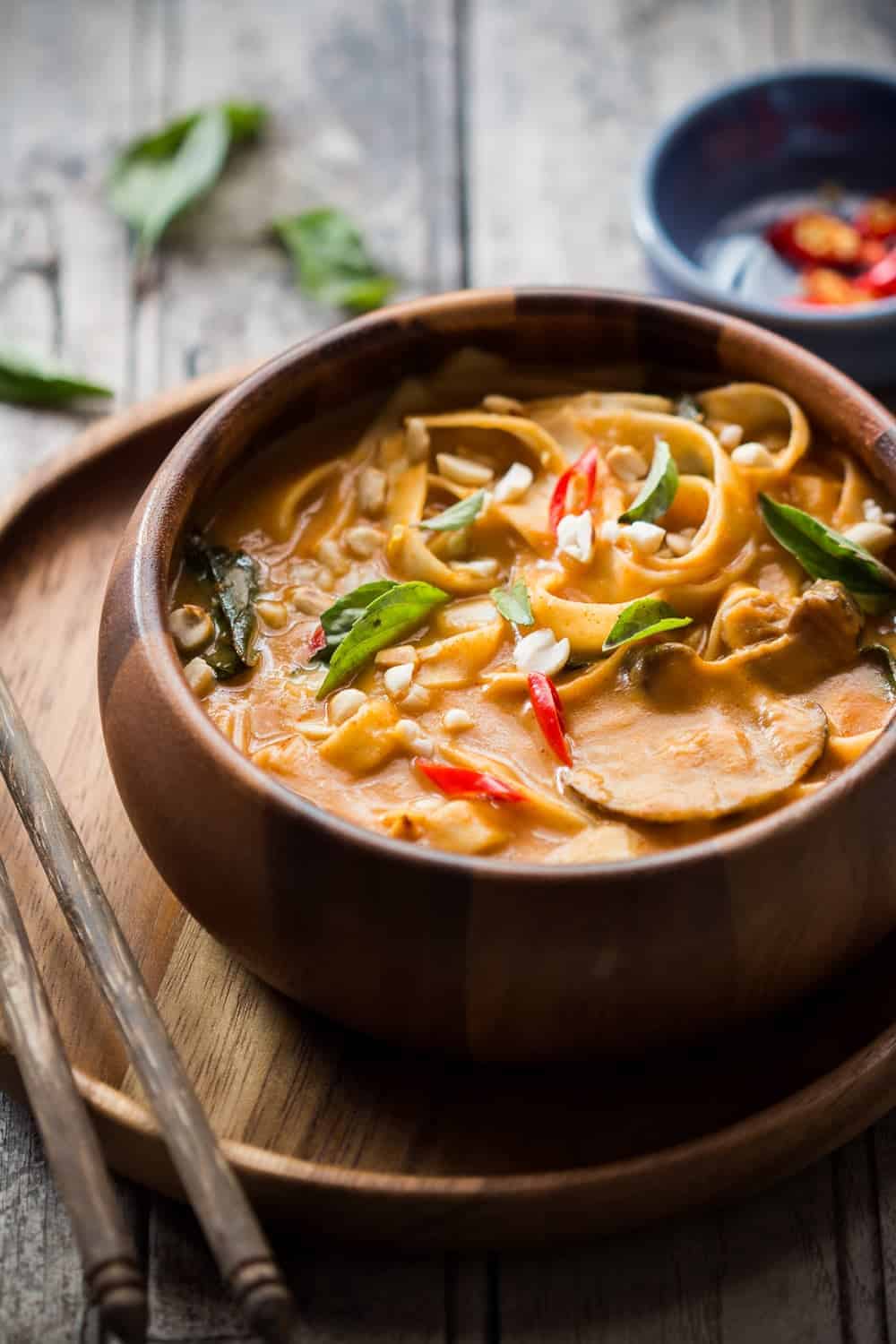 spicy thai curry pumpkin noodle soup served in a brown bowl