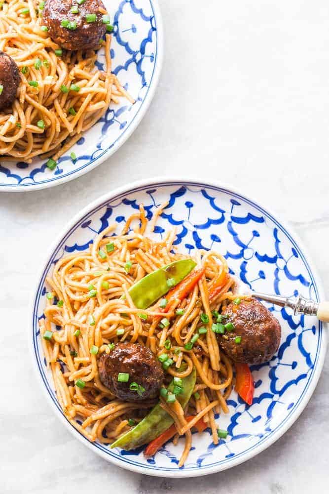 top shot of veg noodles and manchurian served on a white and blue plate