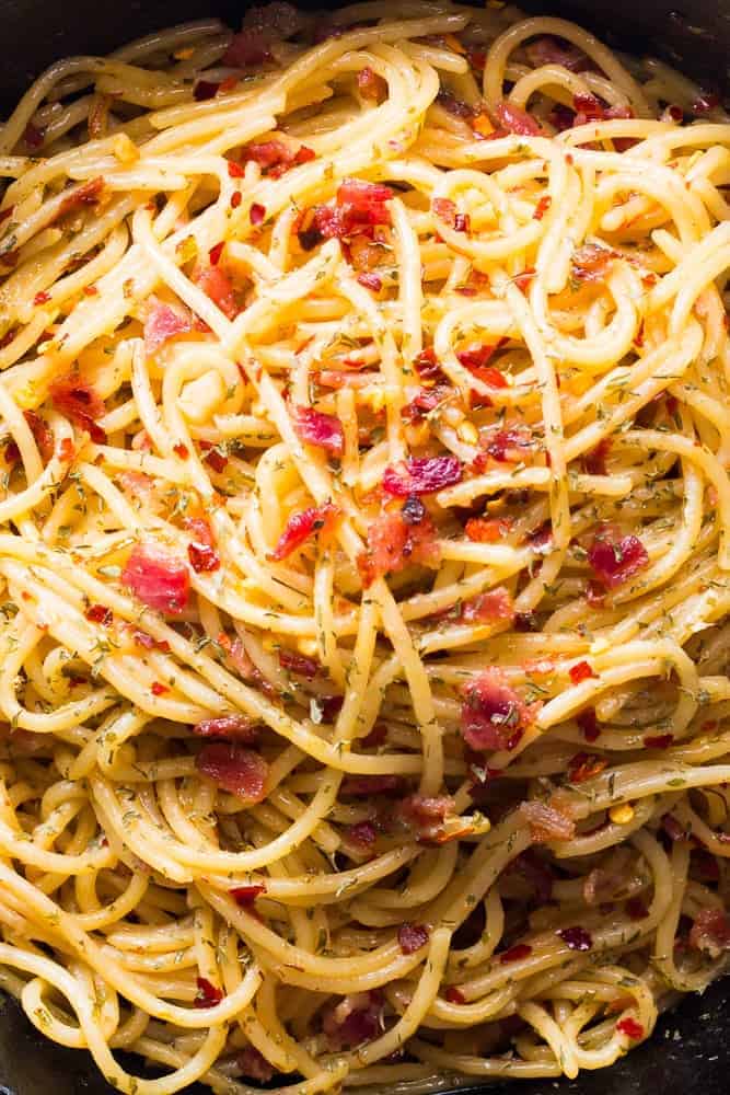 Close up of Bacon Spaghetti Aglio Olio in a black cast iron pan