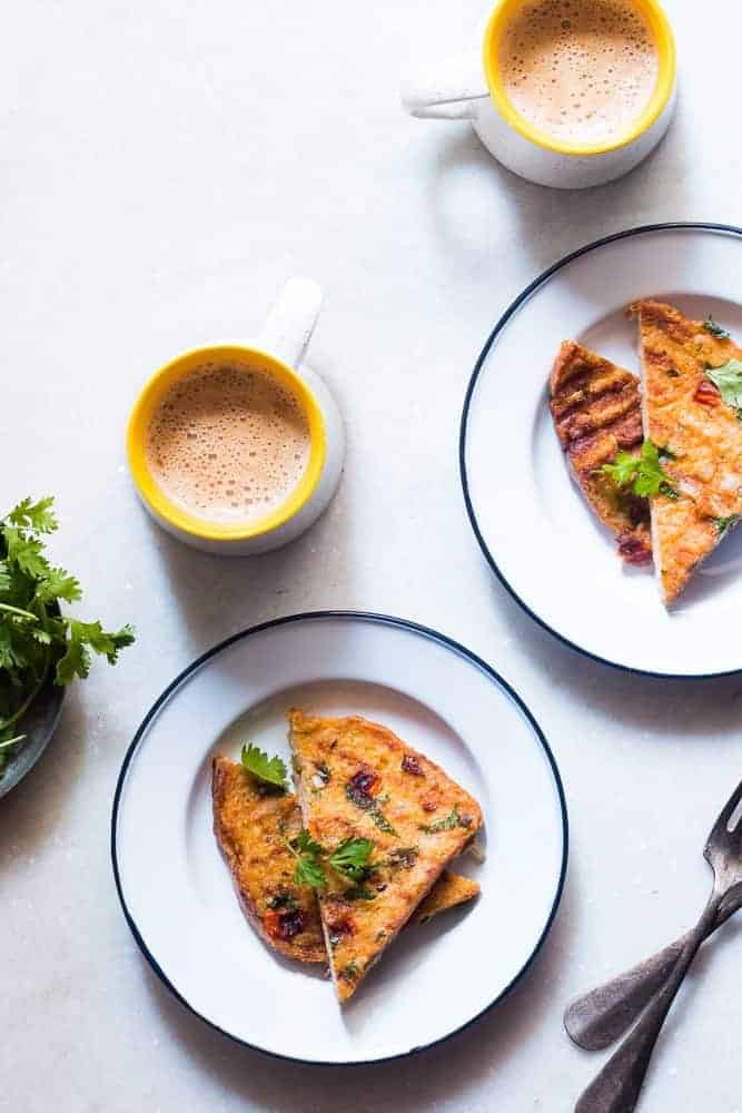 Indian masala egg french toast served in a white plate with hot cups of coffee on the side