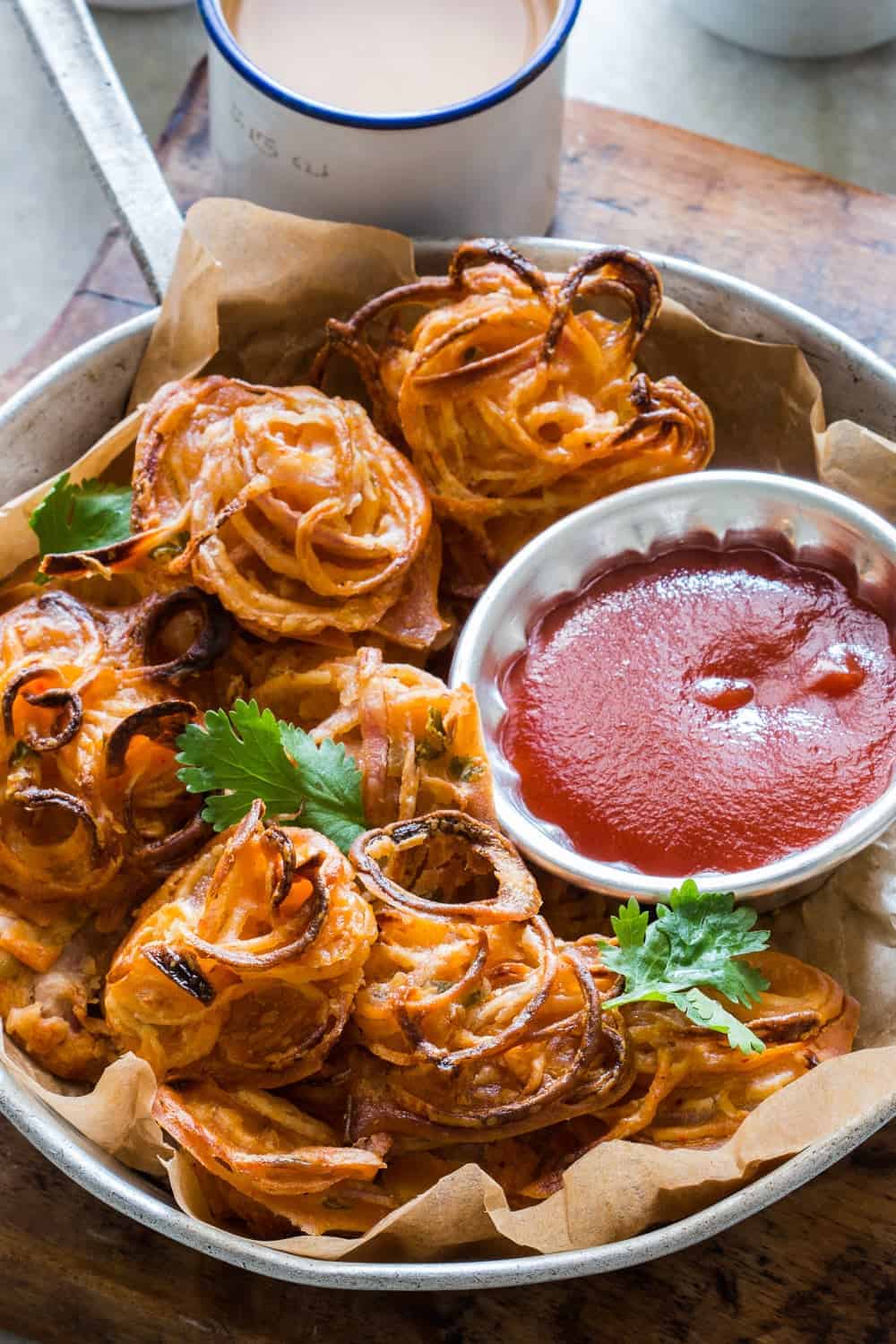 Indians love their pakodas and bhajiyas (fritters) and now there's a guilt-free way to enjoy them with a cup of masala chai. Nobody's ever going to believe these onion pakodas are baked, not fried! Can be made with potato, corn, capsicum and paneer too!