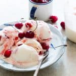 Lychee Cherry Swirl Ice Cream garnished with cherries and served on a white plate.