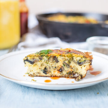 One Pan Indian Masala Omelette Frittata drizzled with sriracha and served on a white plate.