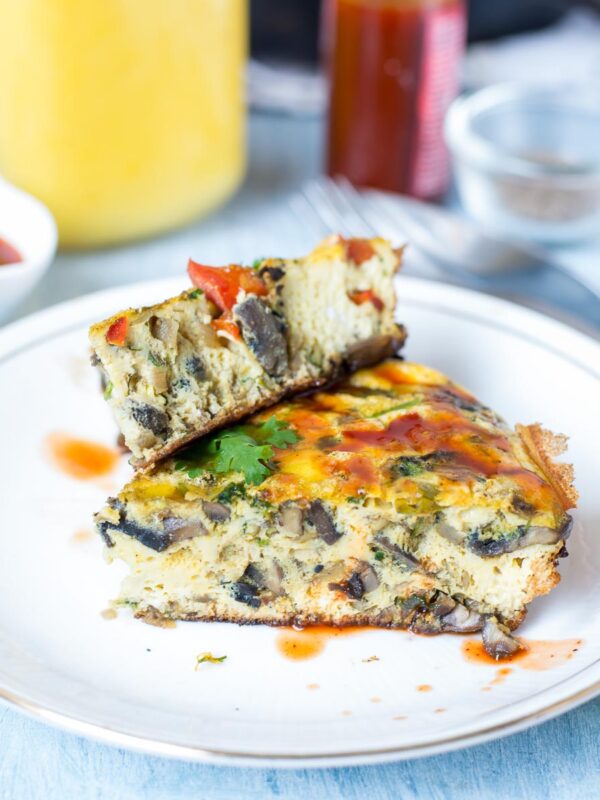 One Pan Indian Masala Omelette Frittata drizzled with sriracha and served on a white plate.