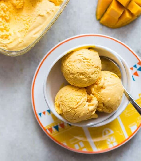 Three scoops of Homemade Mango Cheesecake Ice Cream served in a white bowl.