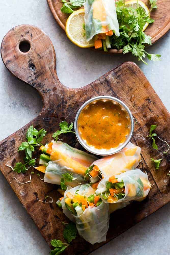 Picture of mango bell pepper spring rolls on a wooden board for the savoury mango recipes roundup