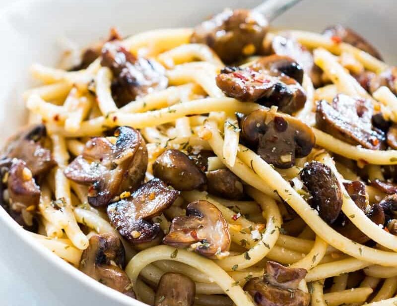 Mushroom spaghetti garnished with parmesan cheese and served in a white bowl.