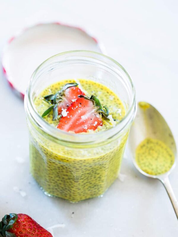 Golden Turmeric Milk Chia Seed Pudding topped with strawberries and served in a glass jar.
