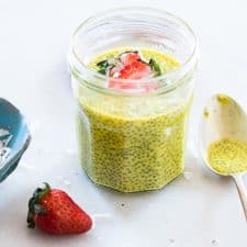 Golden Turmeric Milk Chia Seed Pudding topped with strawberries and served in a glass jar.