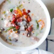 Creamy Slow Cooker Chicken Barley Soup topped with fried bacon and served in a white bowl.
