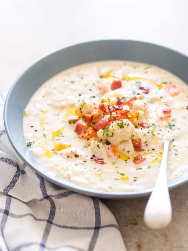Creamy Cauliflower Chowder topped with bacon, olive oil and served in a bowl.