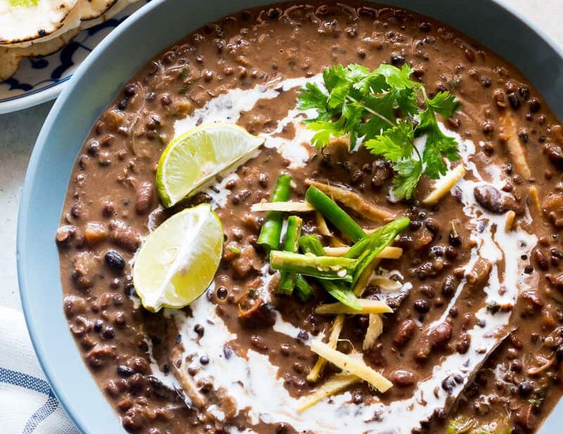 Dal Makhani topped with cream, coriander, ginger, lime and served in a blue bowl.