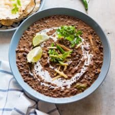 Dal Makhani topped with cream, coriander, ginger, lime and served in a blue bowl.