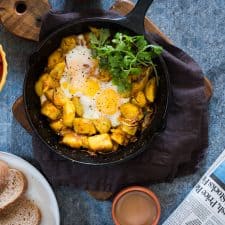 Spiced Indian Potatoes and Egg cooked in a skillet and garnished with coriander.