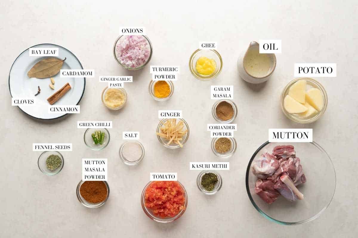 All the ingredients for mutton curry laid out with text to identify them
