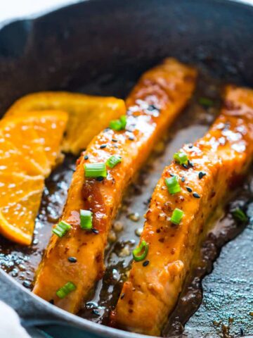 v=Orange Mustard Salmon being seared in a pan.