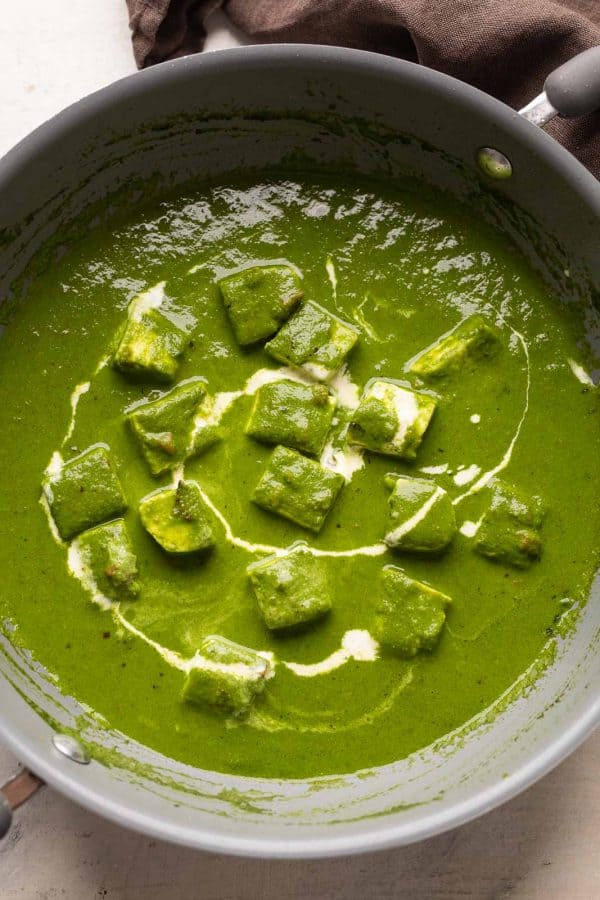 Palak paneer pictures in the pan that it was cooked in with cream drizzled on top