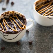 Eggless Banana Chocolate Peanut Butter Mug Cake in a tea cup, topped with peanut butter.