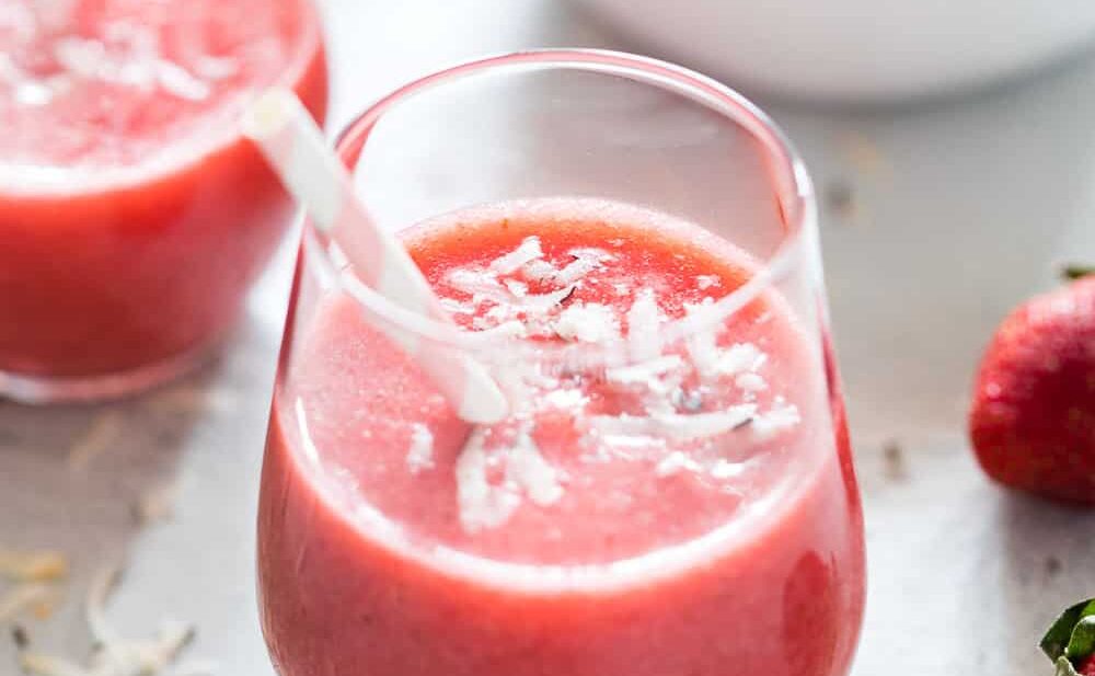 Strawberry Banana Coconut Smoothie garnished with grated coconut and served in a glass with a straw to kick in those tropical vibes!