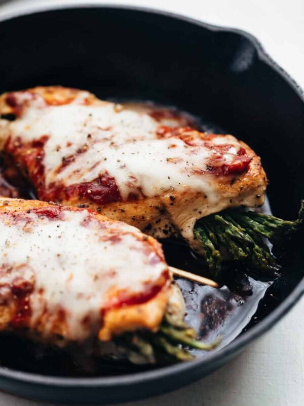 Asparagus Stuffed Chicken Parmesan topped with marinara sauce and prepared in a cast iron pan.