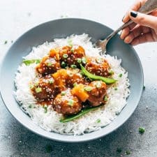 Asian inspired slow cooker teriyaki meatballs with pineapple served with steamed rice in a bowl.