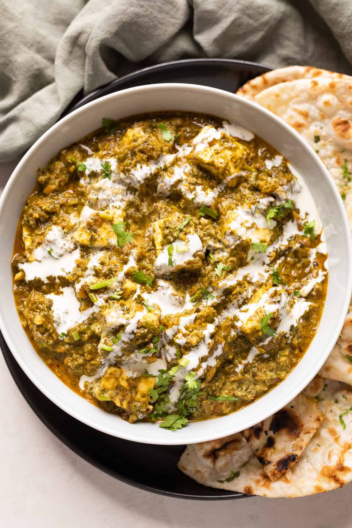 Picture of saag paneer served in a bowl with naan on the side