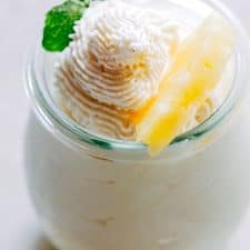 Eggless Pineapple Mousse garnished with mint and a slice of pineapple and served in a mini jar.