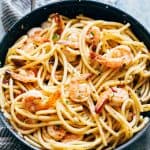 Shrimp Spaghetti Aglio Olio garnished with parsley, parmesan and served in a bowl.